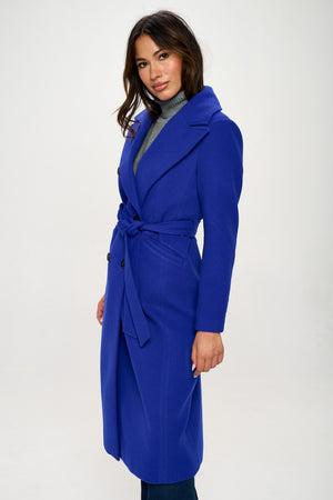 Model wearing a stylish blue double-breasted longline coat with belt, showcasing an elegant and sophisticated look.