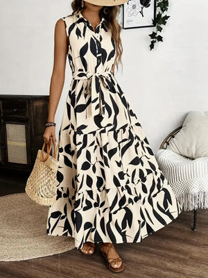 Printed tie waist sleeveless maxi dress in black and cream, featuring a buttoned front and flowy layered skirt.