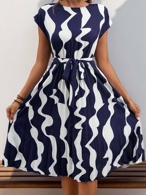 Tied pleated cap sleeve dress in navy and white wavy print, showcasing a flattering silhouette and stylish design.