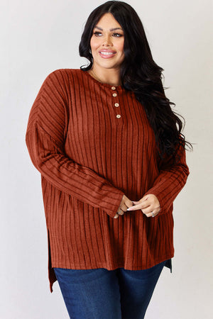 Plus size model wearing a rust ribbed half button long sleeve T-shirt with high-low hem and side slits.