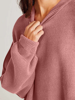 Close-up of a woman wearing a cozy pink side-slit sweater with a relaxed round neck and textured fabric.