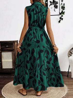 Back view of a sleeveless green maxi dress with a tie waist and leaf print, showcasing a flowy design.