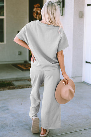 Woman wearing a double take full-size texture short sleeve top and pants set, showcasing a stylish light grey outfit.