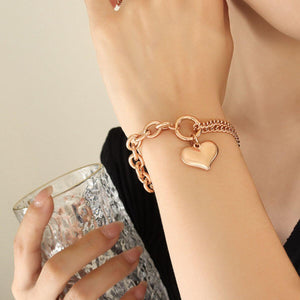Half chunky chain titanium steel bracelet with heart charm, worn on wrist, paired with a stylish glass.