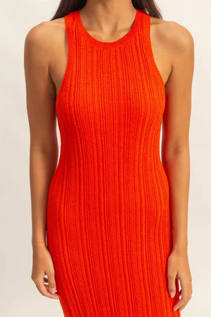 Close-up of a model wearing a vibrant orange ribbed knit bodycon dress with a round neckline.