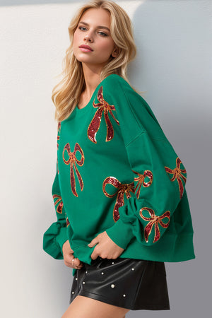 Green Double Take Sequin Bow Sweatshirt with festive bow designs, perfect for stylish winter outfits.