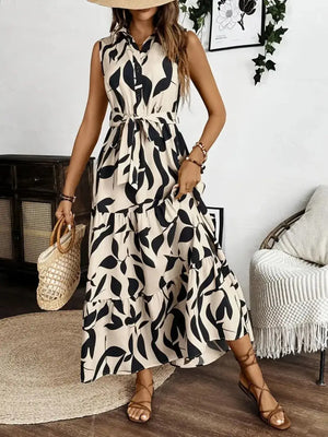 Sleeveless printed maxi dress with tie waist, styled with a straw bag and sandals, perfect for summer outings.
