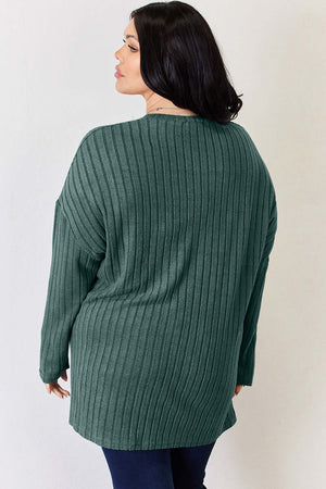 Plus size model in a green ribbed high-low top, showcasing the back design and relaxed fit.