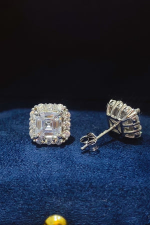 2 carat moissanite stud earrings in platinum-plated sterling silver, elegantly displayed on a blue velvet background.