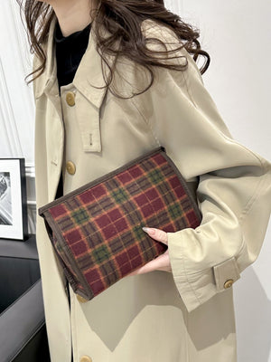 Contrast plaid clutch bag with zipper, small size, perfect for stylish outings, on a model wearing a beige coat.