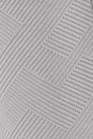 Close-up of textured white fabric with a geometric pattern, ideal for stylish clothing and home decor.