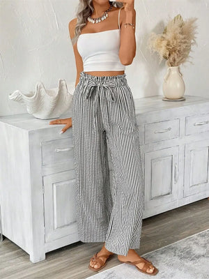 Model wearing full size striped wide leg paper bag pants with tied waist, styled with a white top and accessories.