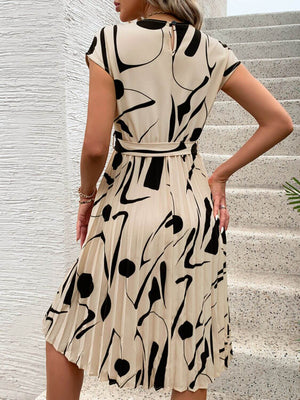 Back view of a tied pleated printed cap sleeve dress, featuring a stylish design in beige and black patterns.