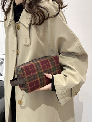Contrast plaid clutch bag in hand, perfect for small essentials, featuring a stylish zipper closure and a chic design.