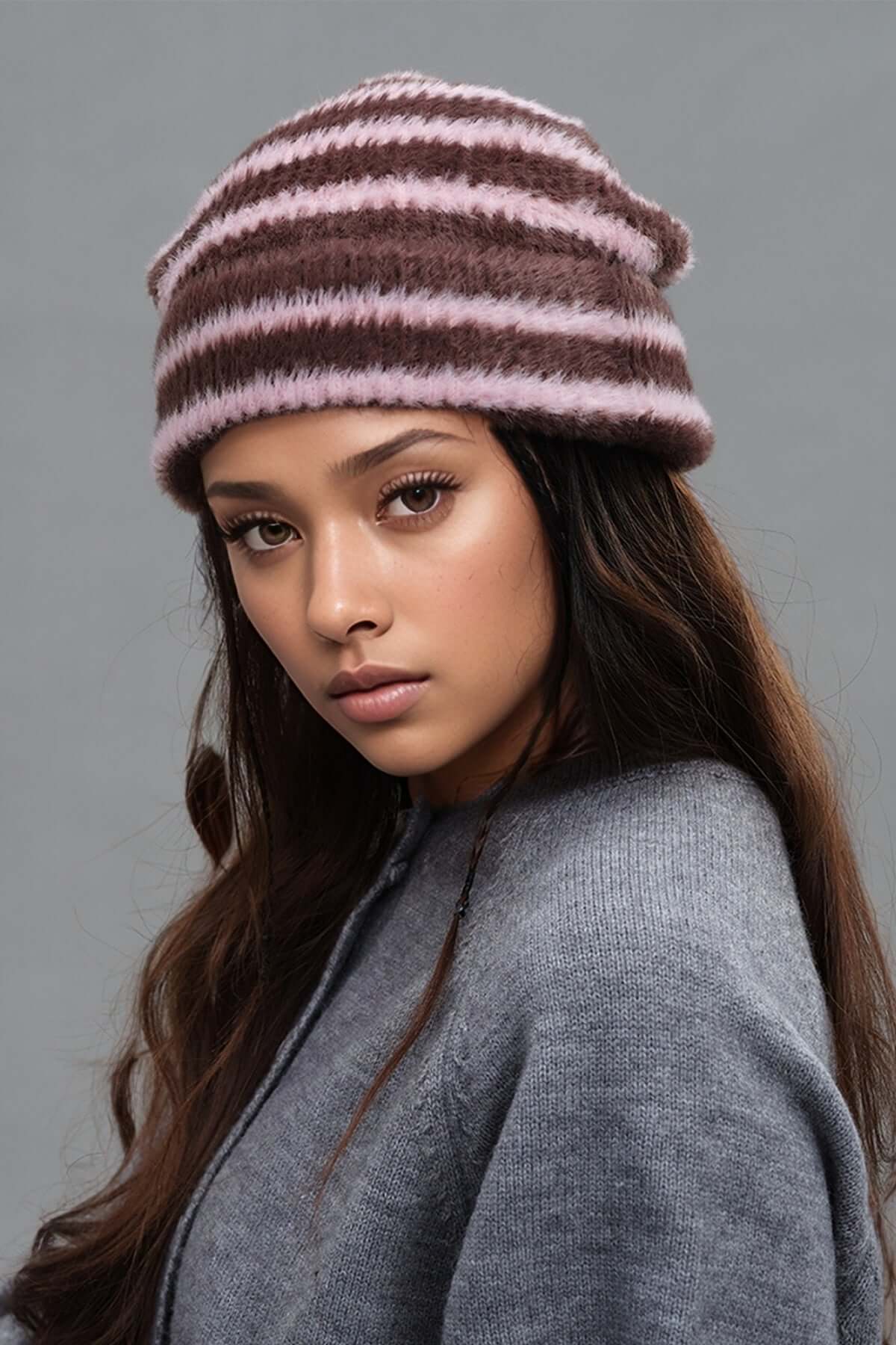 Model wearing a fuzzy contrast striped thermal hat in pink and brown, perfect for cold weather fashion.