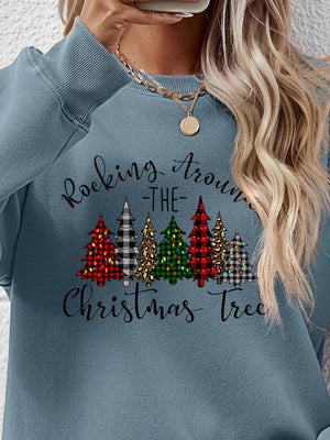 Woman wearing a blue sweatshirt with a Christmas tree graphic and 'Rocking Around the Christmas Tree' text.