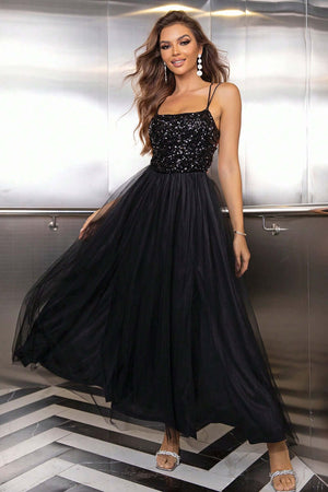 Elegant woman in a black lace-up backless mesh dress with sequined bodice and flowing skirt.