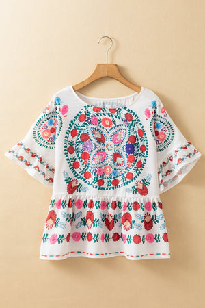 Floral print round neck blouse with ruffle trim, featuring colorful embroidery on a white background.