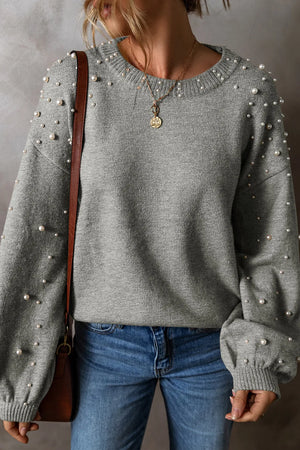 Gray round neck long sleeve sweater with pearl detailing, paired with blue jeans for a stylish look.