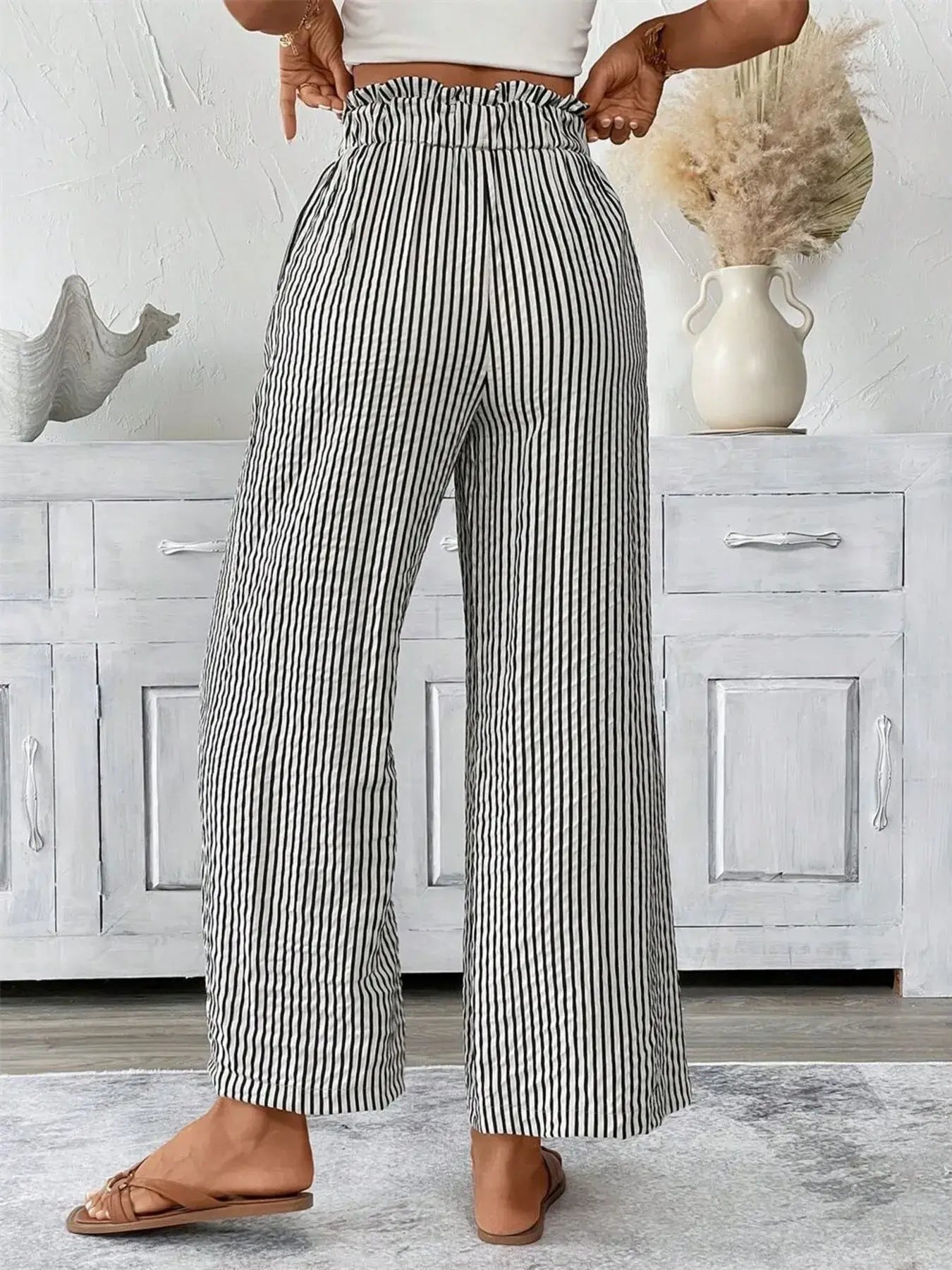 Back view of plus size striped wide leg paper bag pants, featuring a tied waistband and pockets.
