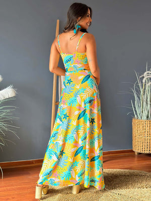 Back view of a woman in a yellow twisted printed V-neck cami dress with tropical designs, perfect for summer styling.