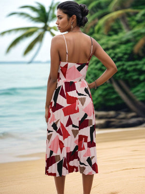 Model in a pleated geometric spaghetti strap dress against a tropical beach background, showcasing a vibrant design.