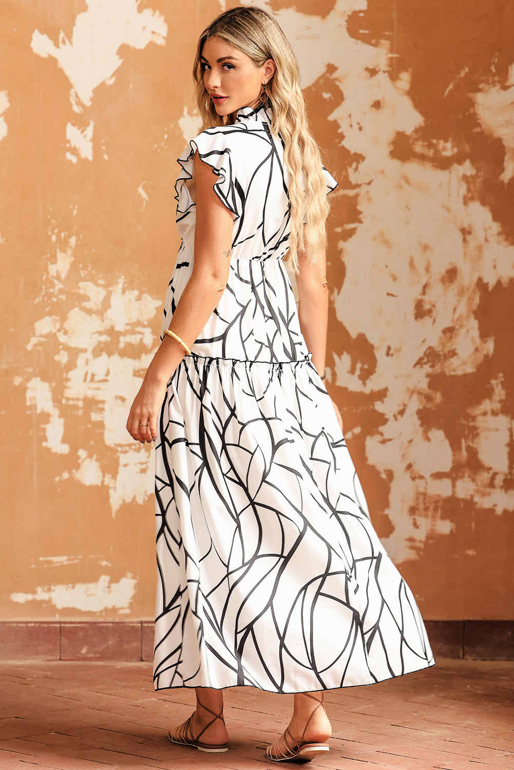 Model wearing a Ruffled Printed Surplice Cap Sleeve Dress, showcasing a black and white design from the back.