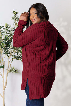 Plus size model wearing a burgundy ribbed long sleeve top with a high-low slit design, showcasing a stylish back view.