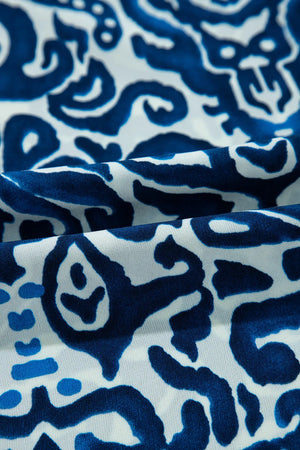 Close-up of printed fabric featuring bold blue abstract patterns on a light background, ideal for stylish dress designs.