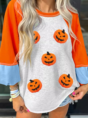 Woman wearing Halloween pumpkin print long sleeve T-shirt, featuring colorful pumpkin graphics and a comfortable fit.