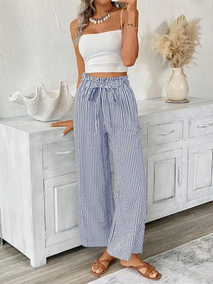Model wearing plus size blue and white striped wide leg paper bag pants with tied waistband.