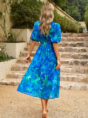 Back view of a blue printed puff sleeve midi dress, showcasing its flowing design and vibrant colors.