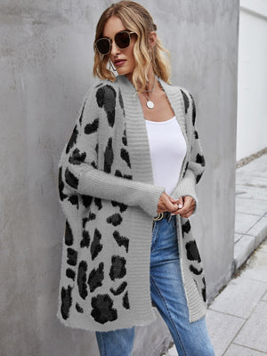 Stylish woman in leopard pattern fuzzy cardigan, open front, paired with a simple top and jeans, showcasing a casual look.