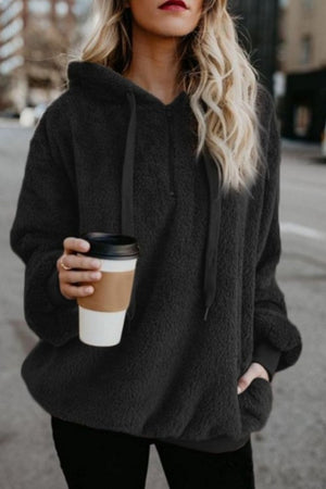 Stylish woman in a gray quarter-zip teddy hoodie holding coffee, showcasing its drawstring and pocketed design.
