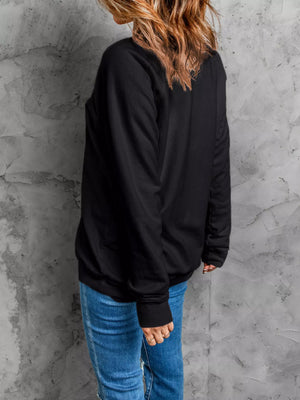 Back view of a woman wearing a black Halloween sweatshirt, showcasing its relaxed fit and sleeve design.