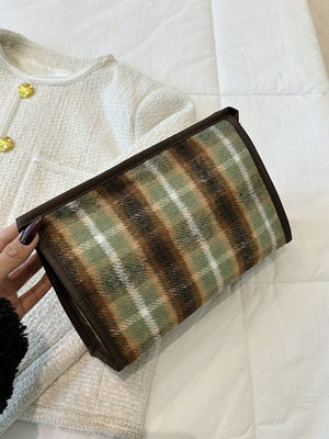 Contrast plaid clutch with zipper in green, brown, and beige, shown on a white textured surface.