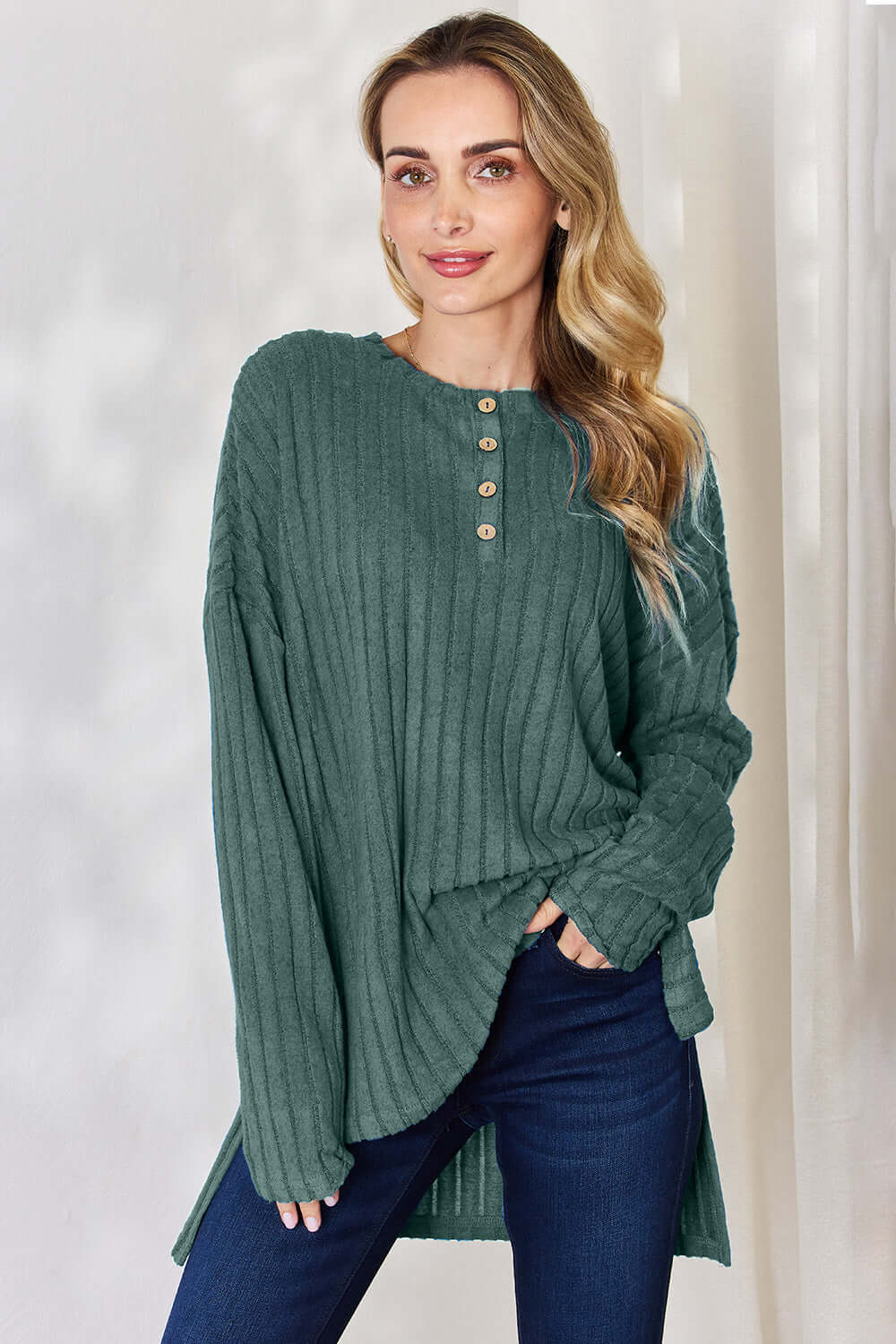 Model wearing a green ribbed half button long sleeve high-low t-shirt with a relaxed fit.