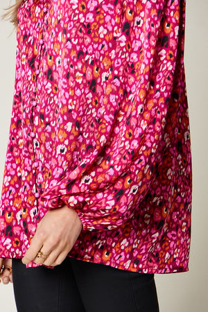Close-up of a women's pink floral long sleeve blouse, featuring a relaxed fit and chic puffed sleeves.