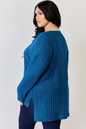 Plus size model wearing a teal ribbed high-low T-shirt with button details and side slits, showcasing style and comfort.