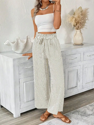 Plus size woman wearing striped wide leg paper bag pants with pockets, styled with a crop top and sandals.