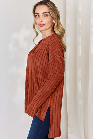 Side view of a model wearing a rust ribbed high-low long sleeve T-shirt with a button detail.
