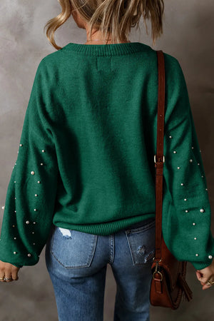 Back view of a woman wearing a green pearl detail long sleeve sweater with a stylish bag.
