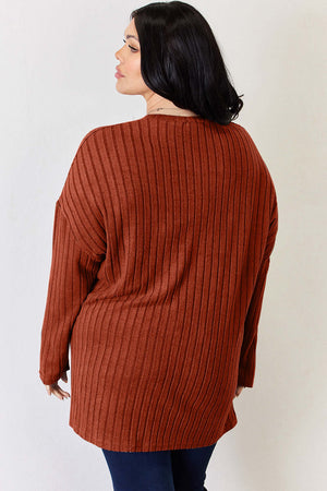 Plus size model wearing a ribbed high-low t-shirt in rust color, showcasing a back view with long sleeves.