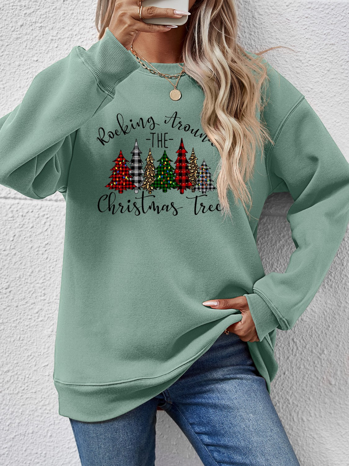 Festive green sweatshirt featuring "Rocking Around the Christmas Tree" with colorful holiday trees.