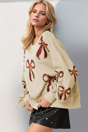 Stylish cream sweatshirt with sequin bow embellishments, perfect for a chic, casual look.