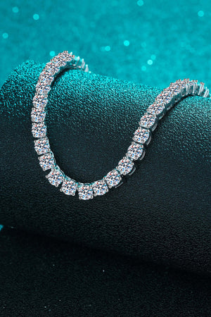Minimalist rhodium-plated moissanite necklace resting on a textured surface, showcasing its sparkling elegance.