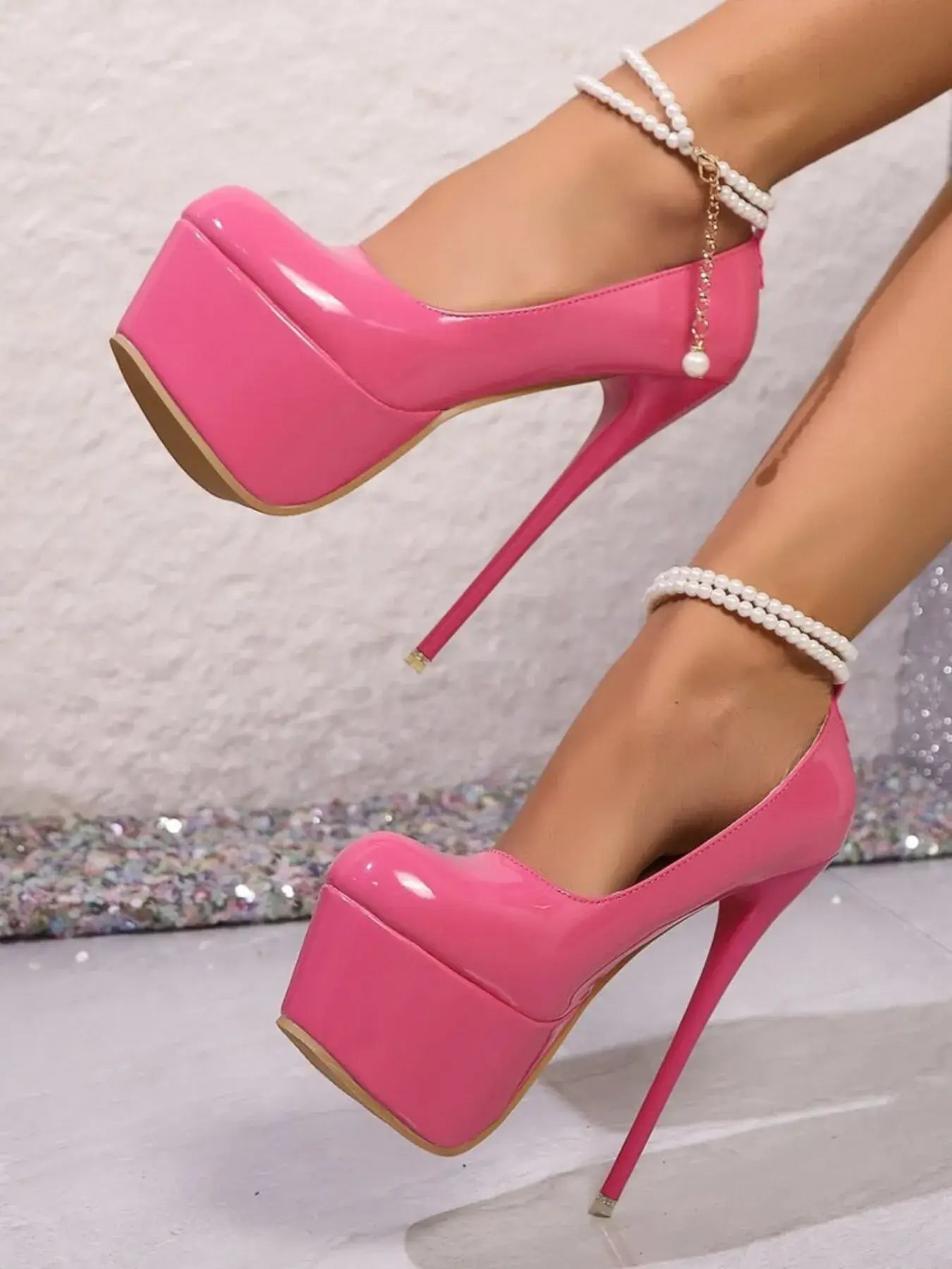 Point toe pink platform stilettos with high heels, featuring elegant ankle straps and a glossy finish.