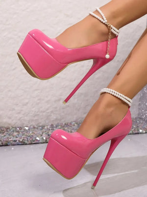 Point toe pink platform stilettos with high heels, featuring elegant ankle straps and a glossy finish.