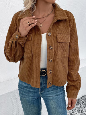 Collared neck button front jacket in brown, featuring pockets and textured fabric, styled with a white top and blue jeans.