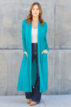 Model wearing a Basic Bae teal open front long sleeve cover up with pockets, styled with jeans and heels.